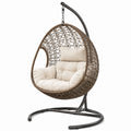 Sedia sospesa in rattan sintetico con cuscini in poliestere beige e struttura in metallo